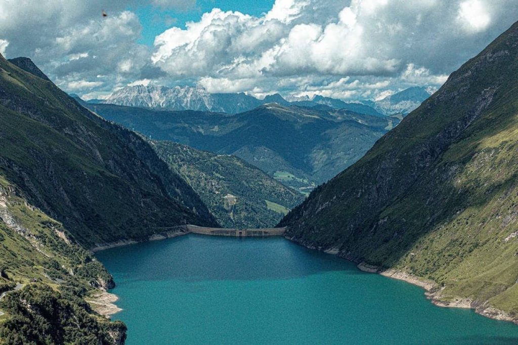 Blauer Alpen-Stausee zwischen grünen Bergen nahe Piesendorf, Region Zell am See Kaprun